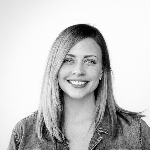 Smiling woman with straight, shoulder-length hair wearing a denim jacket, facing the camera against a plain background.